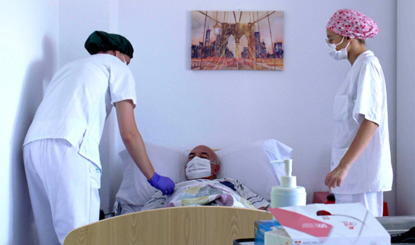 Dos trabajadoras de una residencia de mayores medicalizada atienden a una persona enferma.