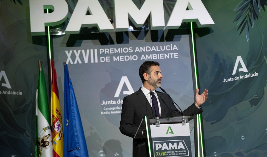 Ampliar imagen: Consejero de Medio Ambiente introduciendo la ceremonia de premios, junto a las banderas de Andalucía, España y la Unión Europea