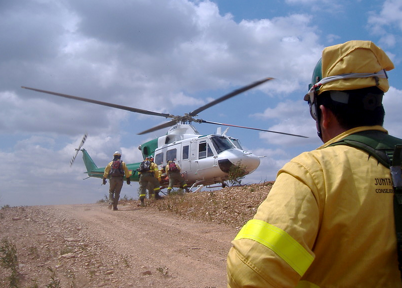 Ampliar imagen: agentes del INFOCA subiendo a un helicóptero para desplazarse rápidamente hasta un incendio