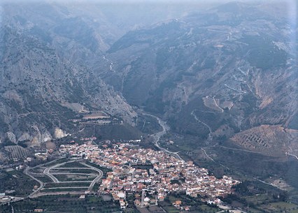 Fotografía aérea del pueblo de Nigüelas en una falla de terreno verde con montañas al fondo