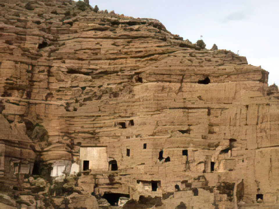 Ampliar imagen: montaña arcillosa con cuevas hechas por el ser humano y algunos árboles en la cima