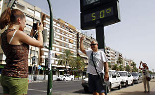 Turistas se fotografían junto a un termómetro en una calle andaluza. (Fotos EFE)