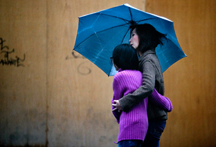 Viandantes paseando bajo la lluvia (Efe). 