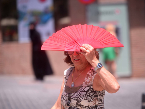 Una señora se protege del sol con un abanico.