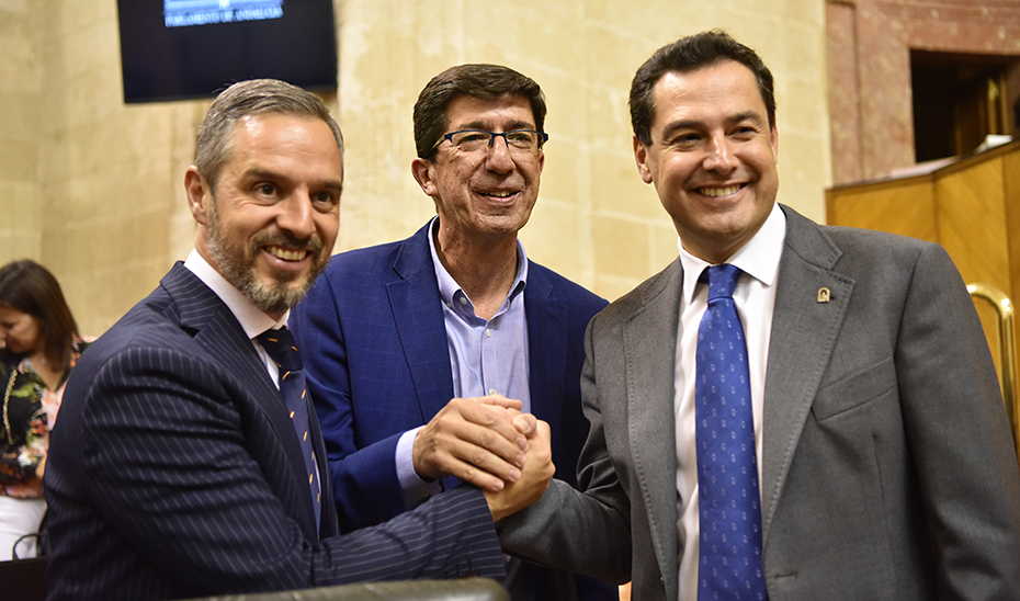 Juanma Moreno, Juan Marín y Juan Bravo se felicitan después del debate de totalidad del Presupuesto, en el Parlamento.