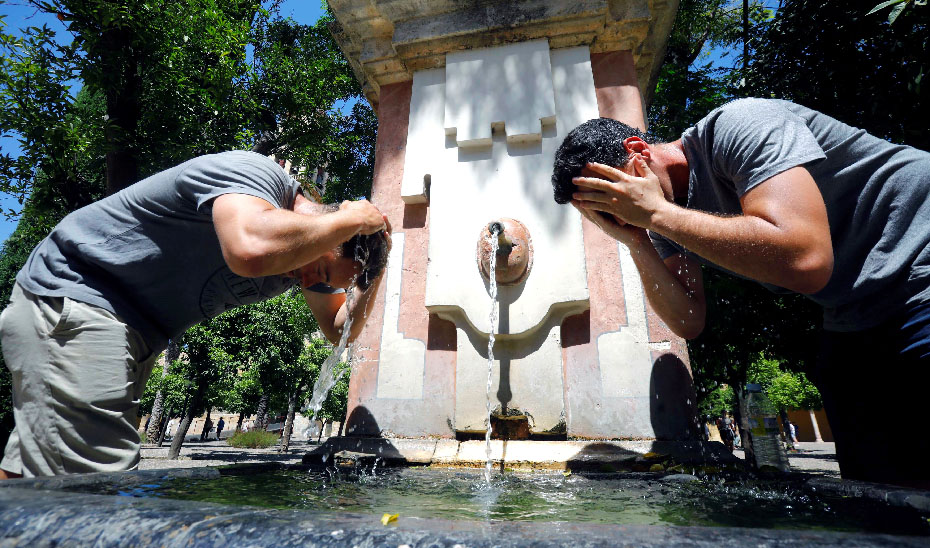 Dos hombres se refrescan en una fuente (Foto: Efe).