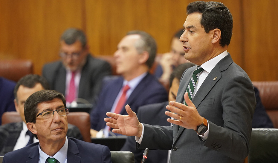 El presidente de la Junta, Juanma Moreno, responde desde su escaño ante la mirada de Juan Marín.