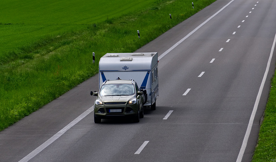 Un coche con caravana transita por una carretera.