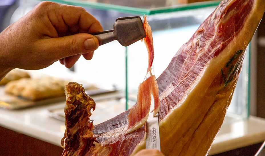 Un cortador profesional de jamón saca lonchas de una pata de cerdo ibérico.
