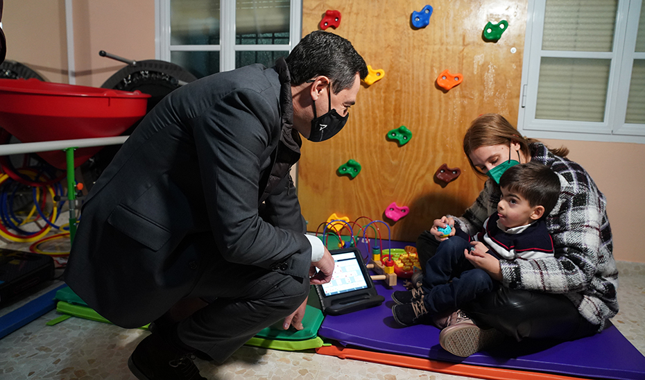 Juanma Moreno charla con un niño y su madre, en el centro 'Pablo Ramírez García' de El Coronil.