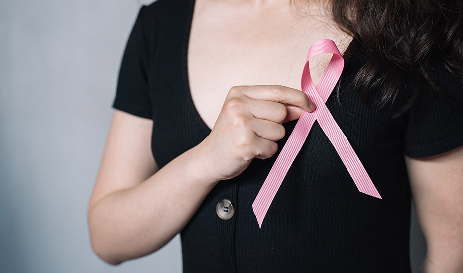 Una mujer se coloca el lazo rosa en solidaridad con las afectadas por cáncer de mama.