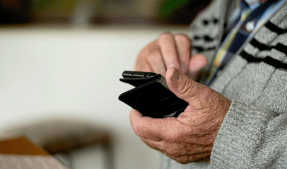 Un hombre de avanzada edad consulta su teléfono móvil en una residencia.