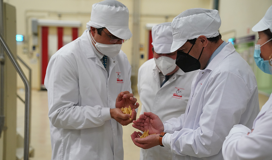 Juanma Moreno supervisa uno de los productos de Pastas Gallo durante su visita la fábrica.