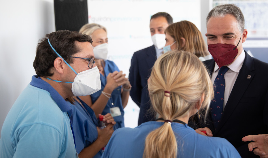 El consejero Elías Bendodo conversa con unos enfermeros en el inicio del proceso de vacunación en la empresa Alestis Aerospace.
