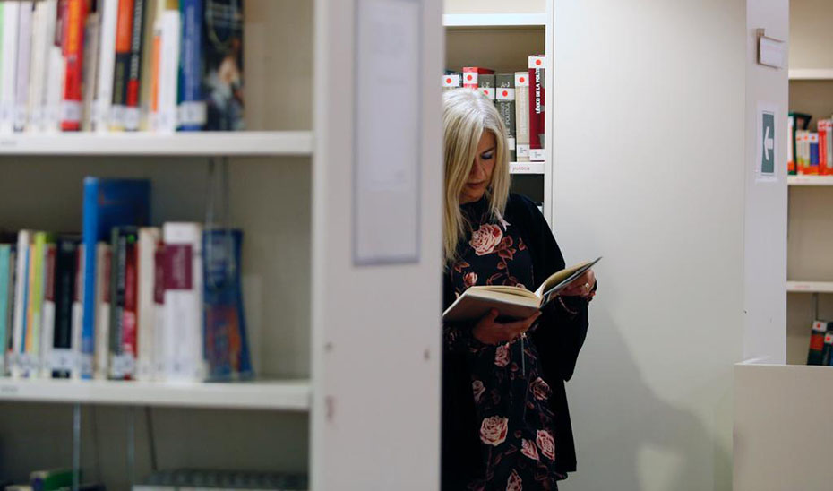 La consejera de Cultura, Patricia del Pozo, consulta un libro en una biblioteca pública.