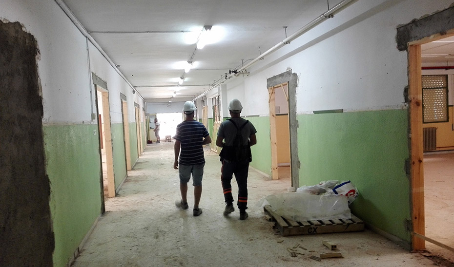 Dos trabajadores caminan por los pasillos de un centro escolar en construcción.