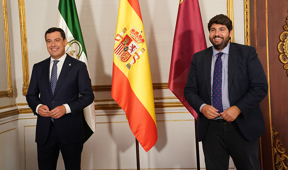 Moreno y López Miras posan ante los gráficos ante las banderas nacional y autonómicas.