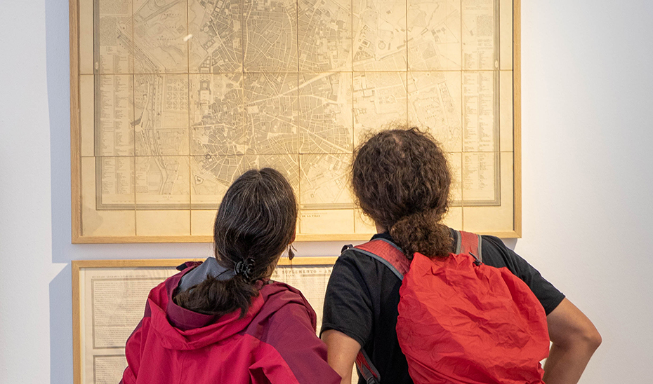 Dos asistentes a la exposición observan un mapa de Madrid elaborado por Francisco Coello.
