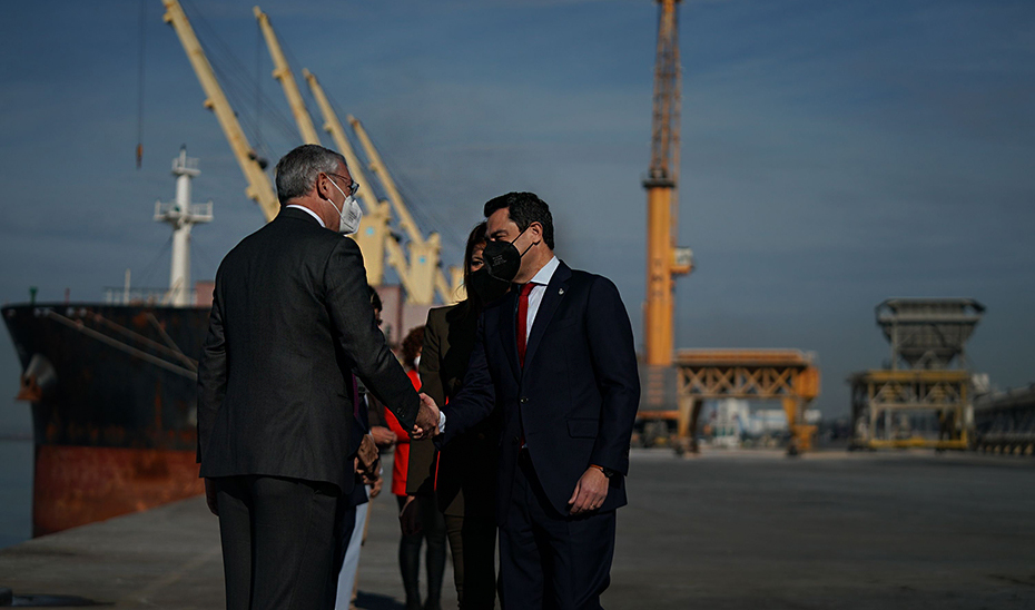 El presidente de la Junta saluda a las autoridades a su llegada a las instalaciones del Puerto de Huelva.