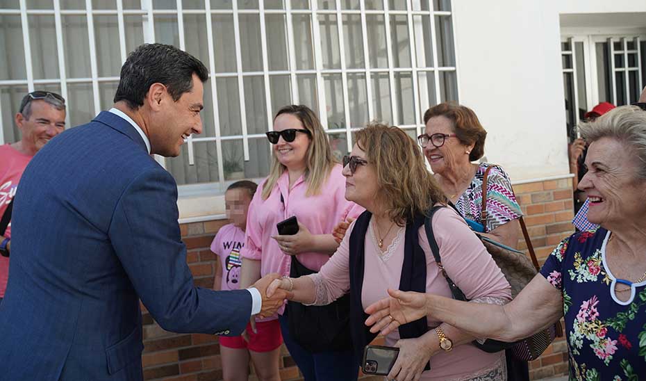 El presidente Juanma Moreno saluda a unas vecinas a su llegada a Antas.