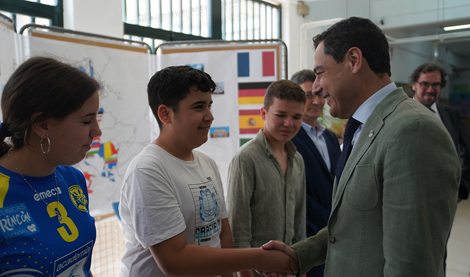 Juanma Moreno saluda a los alumnos del IES Axati en la localidad sevillana de Lora del Río.