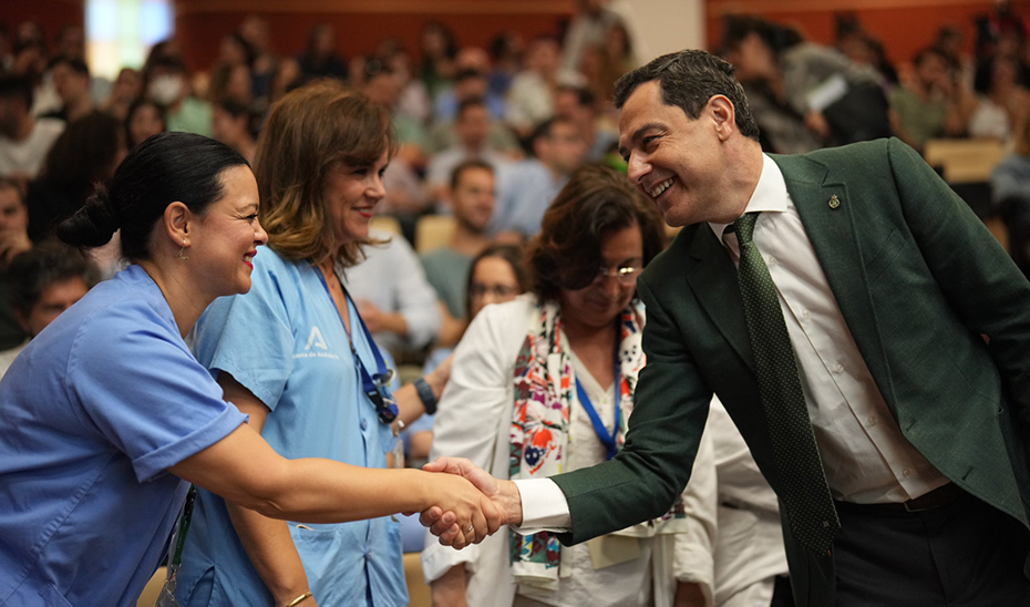 Moreno saluda a una sanitaria del Hospital Virgen del Rocío de Sevilla durante el acto de bienvenida a los nuevos residentes.