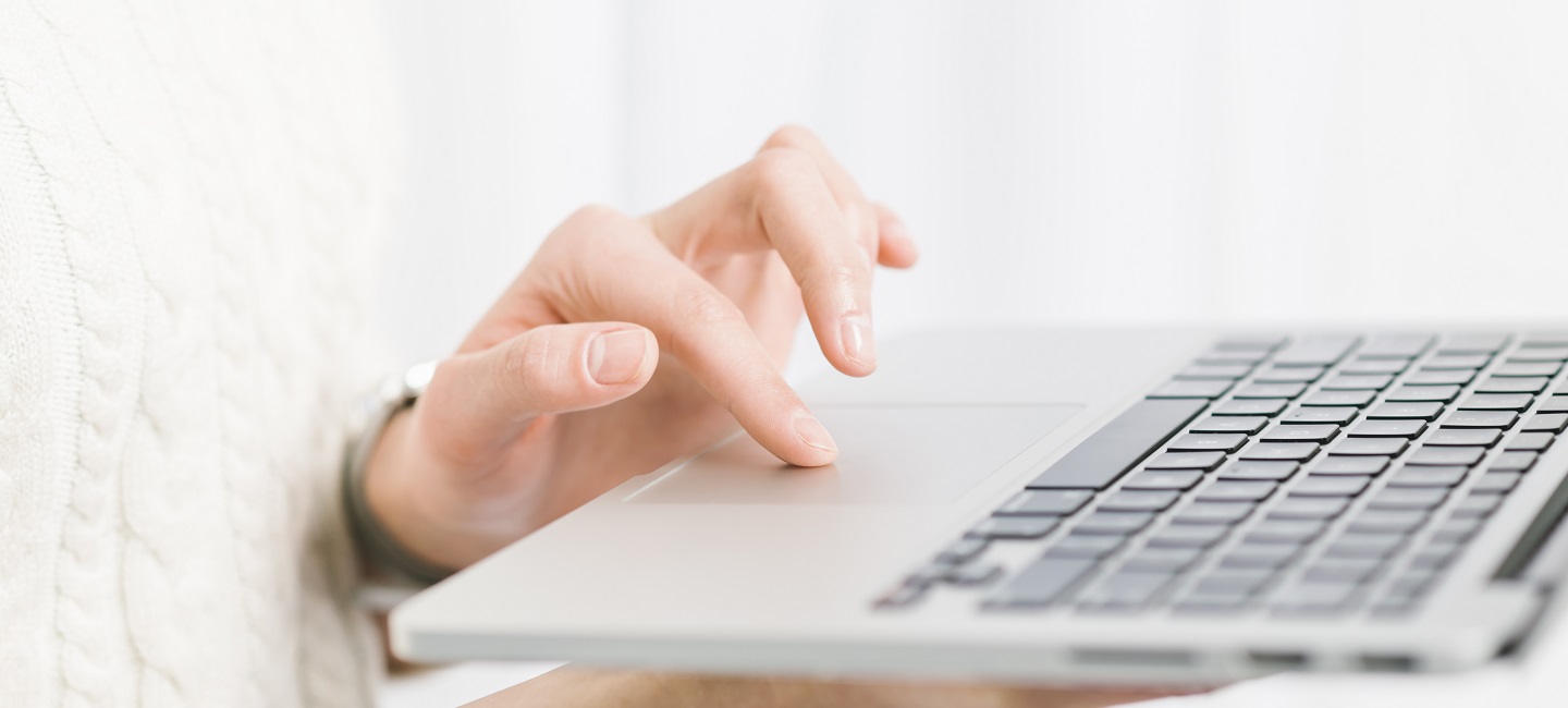 Una persona maneja con el dedo índice de la mano el ratón de un ordenador portátil